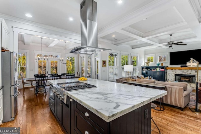 kitchen featuring stainless steel appliances, a breakfast bar, light wood-style floors, beamed ceiling, and island exhaust hood