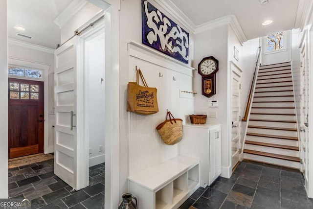 mudroom featuring stone finish flooring, visible vents, crown molding, and a barn door