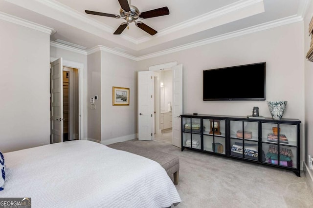 carpeted bedroom with baseboards, a raised ceiling, a ceiling fan, ensuite bathroom, and crown molding