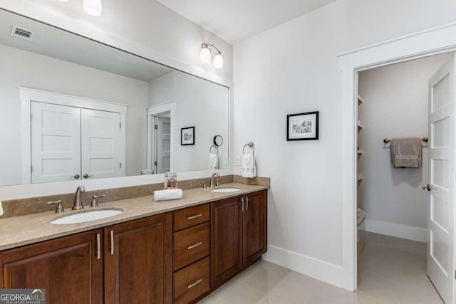 full bathroom with double vanity, baseboards, visible vents, and a sink