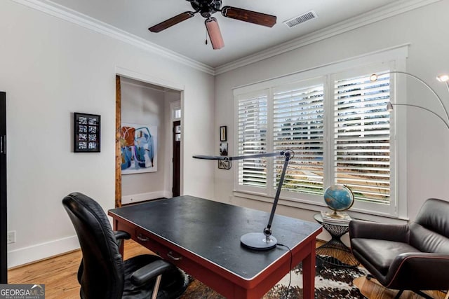 office space featuring a ceiling fan, baseboards, visible vents, light wood finished floors, and crown molding