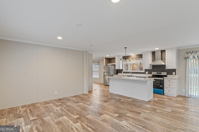 kitchen featuring stainless steel appliances, white cabinetry, wall chimney range hood, a center island, and light wood finished floors