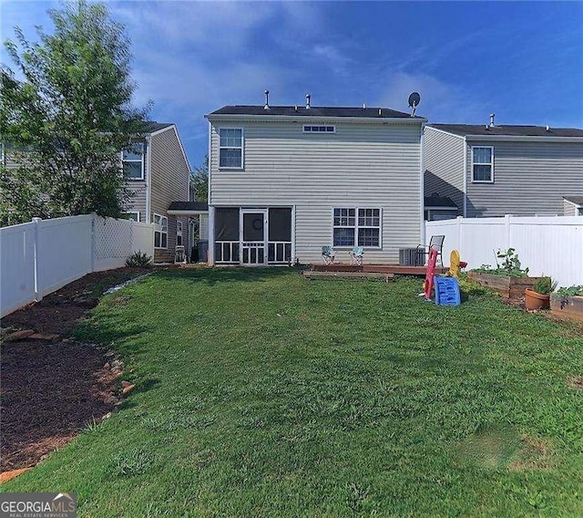 rear view of property with a lawn, a vegetable garden, a fenced backyard, and a sunroom