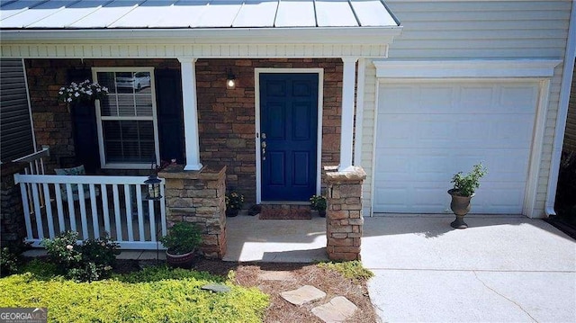 view of exterior entry with metal roof, a standing seam roof, stone siding, and covered porch