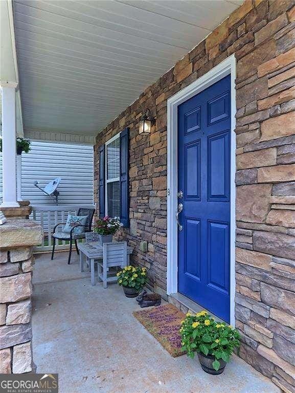 view of exterior entry with covered porch and stone siding