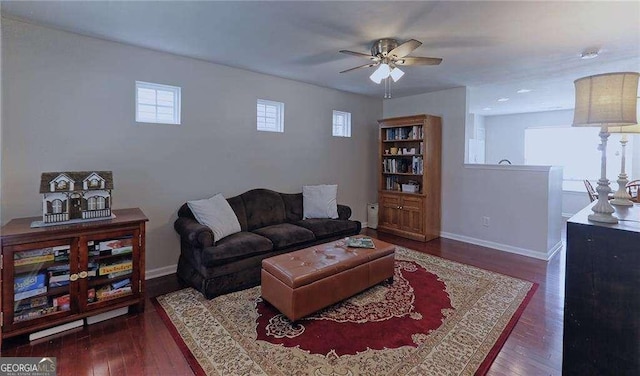 living room with ceiling fan, baseboards, and wood finished floors