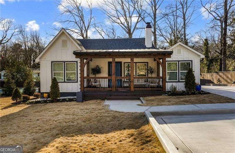 view of front of home with covered porch, board and batten siding, a chimney, and a front yard