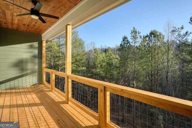 wooden deck featuring a ceiling fan and a wooded view