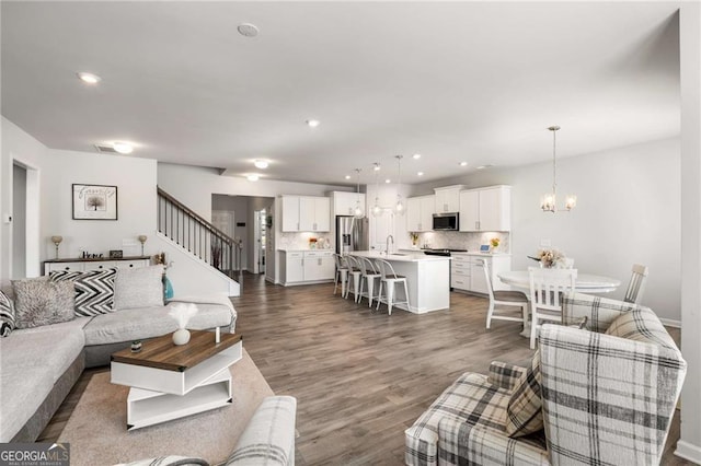 living area with an inviting chandelier, stairs, dark wood finished floors, and recessed lighting