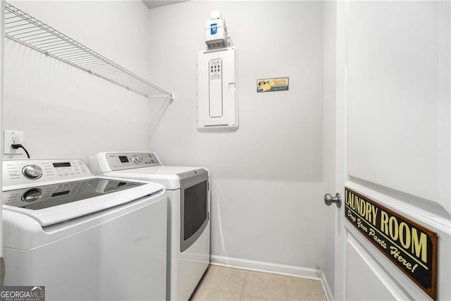 clothes washing area with laundry area, separate washer and dryer, light tile patterned flooring, and baseboards