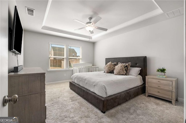 bedroom featuring light carpet, a tray ceiling, visible vents, and baseboards