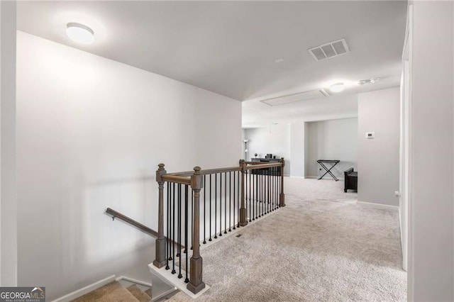 hall with carpet floors, an upstairs landing, visible vents, and baseboards