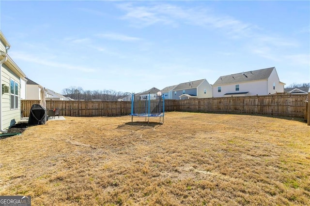 view of yard with a fenced backyard, a trampoline, and a residential view