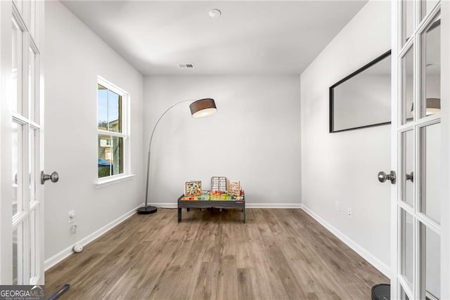 interior space with french doors, wood finished floors, visible vents, and baseboards