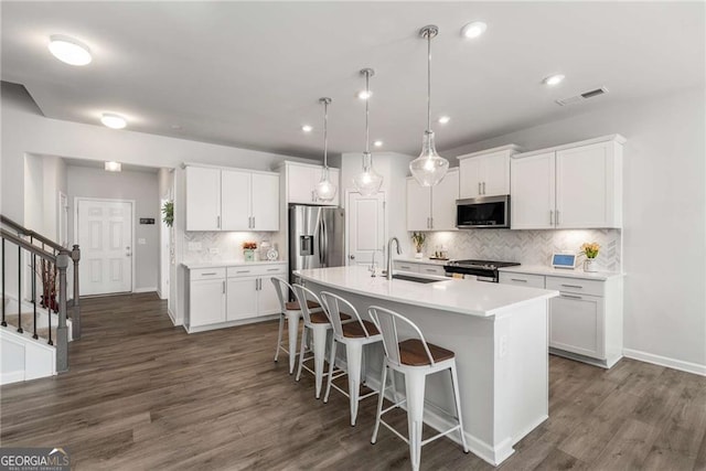 kitchen with a center island with sink, visible vents, stainless steel appliances, a kitchen bar, and a sink