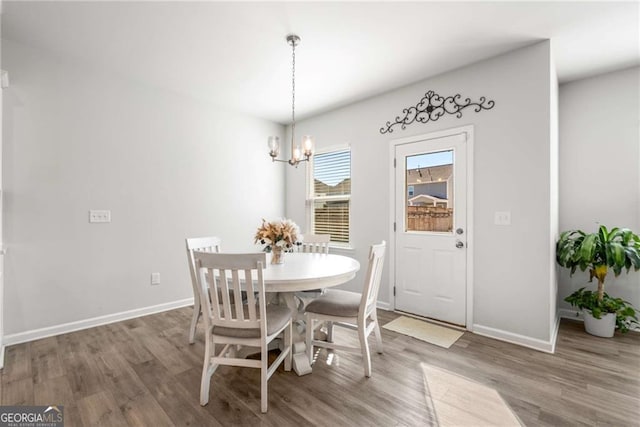 dining space with a notable chandelier, baseboards, and wood finished floors