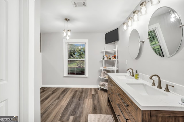 bathroom featuring baseboards, visible vents, a sink, and wood finished floors