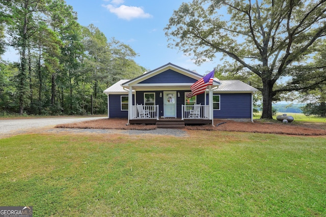 view of front of home featuring covered porch, metal roof, and a front yard