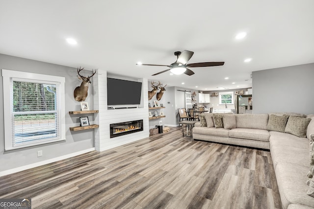 living area featuring recessed lighting, a large fireplace, a healthy amount of sunlight, and wood finished floors