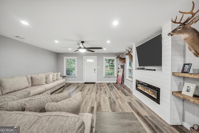 living area with recessed lighting, visible vents, a fireplace, and wood finished floors