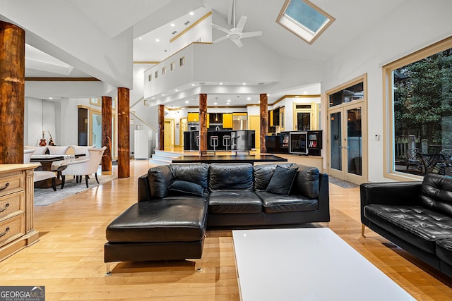 living area featuring a skylight, french doors, recessed lighting, light wood-style flooring, and high vaulted ceiling