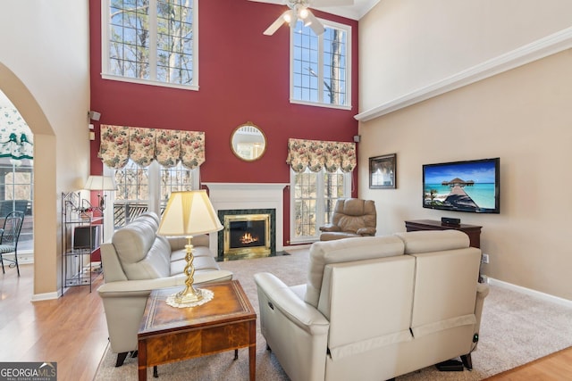 living area with baseboards, a fireplace with flush hearth, arched walkways, and wood finished floors