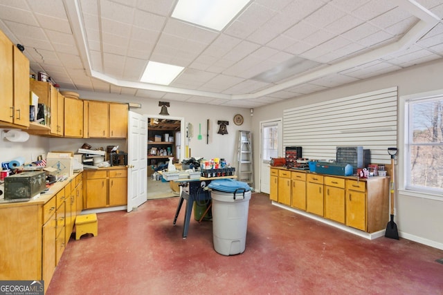 kitchen featuring a paneled ceiling, finished concrete flooring, and baseboards