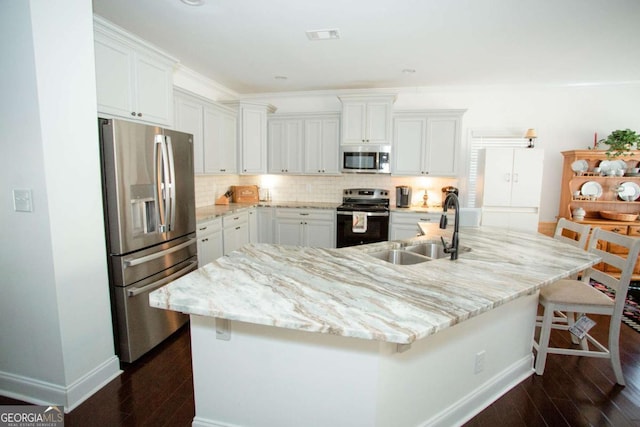 kitchen with appliances with stainless steel finishes, dark wood-style flooring, a sink, and decorative backsplash