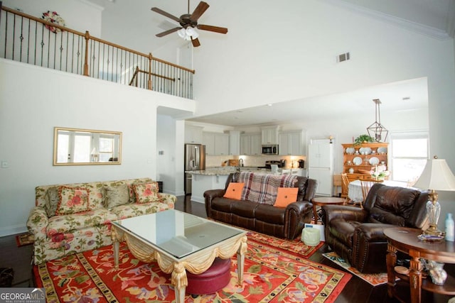 living room with dark wood-style flooring, crown molding, visible vents, a ceiling fan, and baseboards