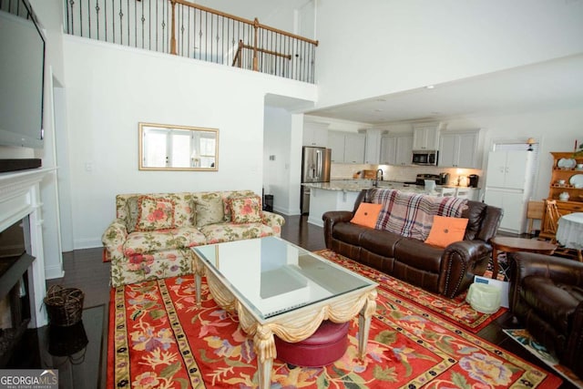 living room featuring a fireplace, wood finished floors, a towering ceiling, and baseboards