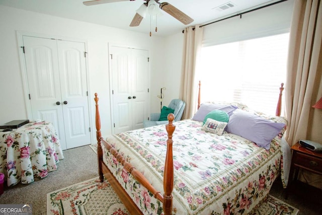 carpeted bedroom with ceiling fan, visible vents, and multiple closets