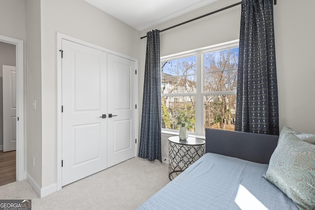 carpeted bedroom with a closet and baseboards