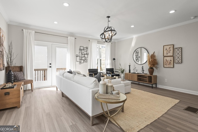 living area featuring visible vents, crown molding, baseboards, and wood finished floors