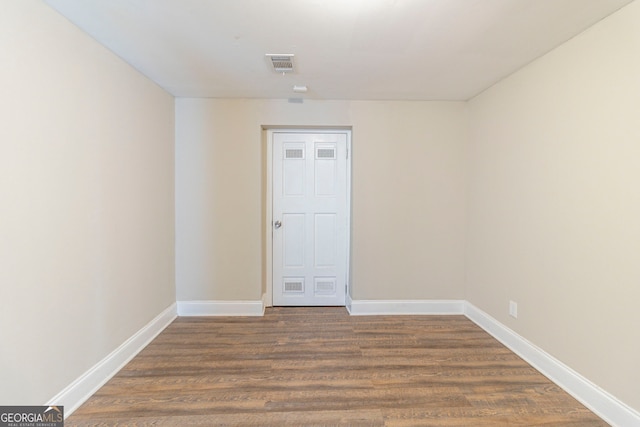 empty room featuring wood finished floors, visible vents, and baseboards