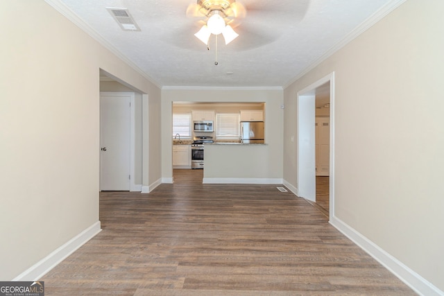 interior space featuring ornamental molding, visible vents, baseboards, and wood finished floors