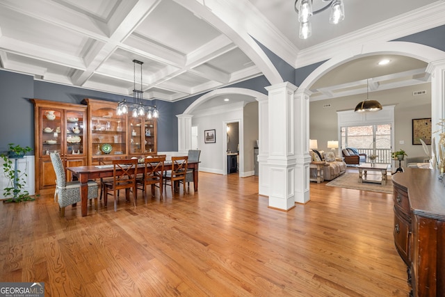 dining room with decorative columns, light wood-style flooring, and beamed ceiling