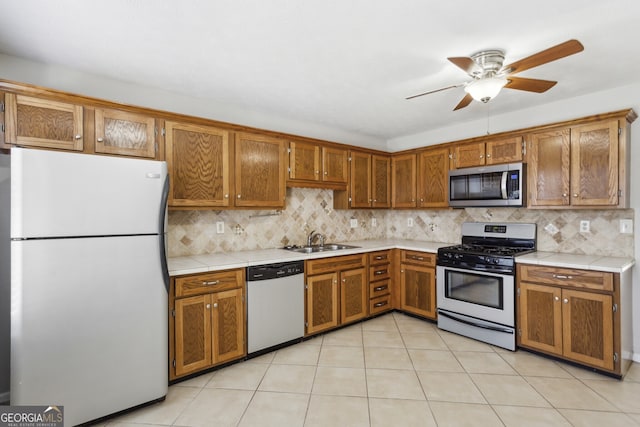 kitchen with appliances with stainless steel finishes, brown cabinets, a sink, and backsplash