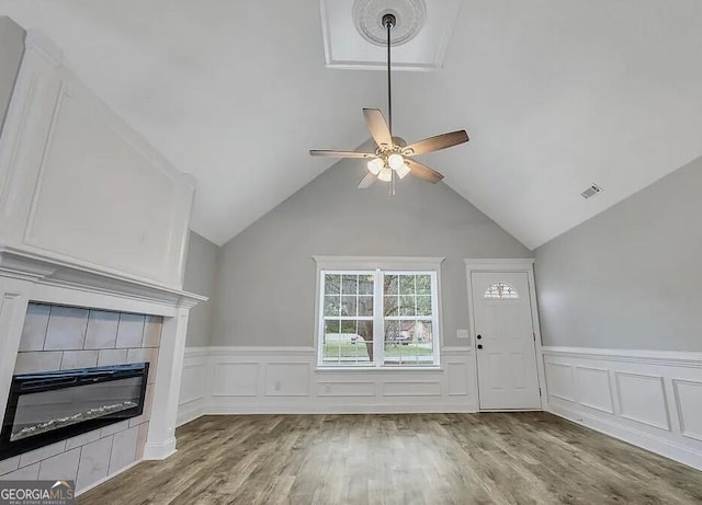 unfurnished living room with visible vents, a tiled fireplace, wood finished floors, and a ceiling fan