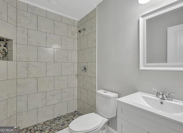 bathroom featuring tiled shower, vanity, and toilet