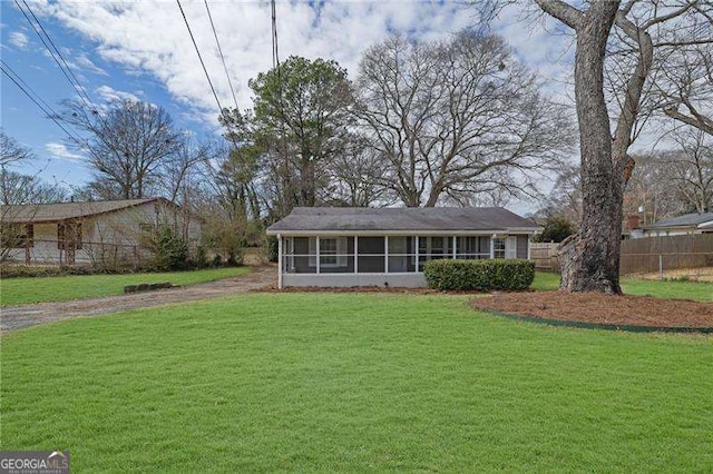 view of front of house with a front lawn, fence, and a sunroom