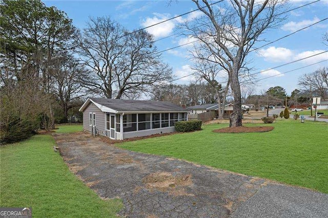 view of front of house featuring driveway, a front yard, and a sunroom