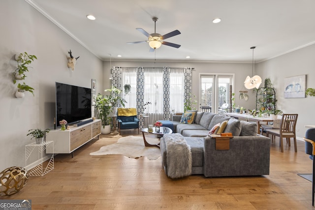 living area featuring a ceiling fan, baseboards, light wood finished floors, recessed lighting, and crown molding