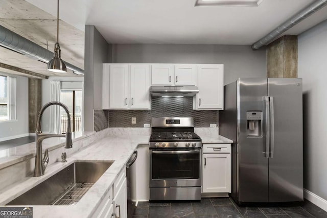 kitchen with under cabinet range hood, a sink, white cabinets, appliances with stainless steel finishes, and light stone countertops