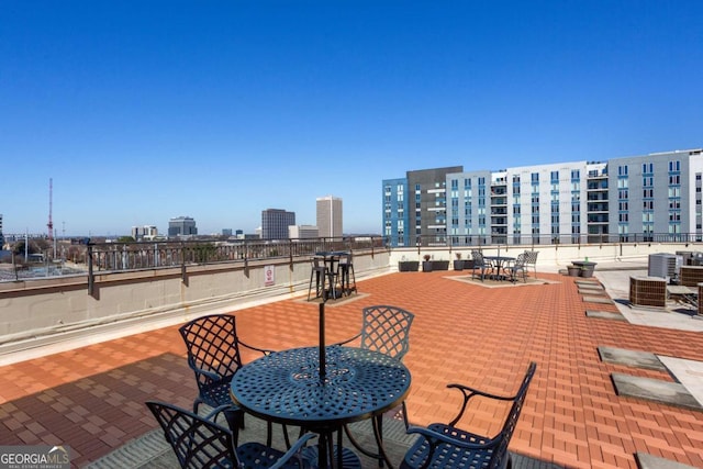 view of patio with central AC, outdoor dining space, and a city view