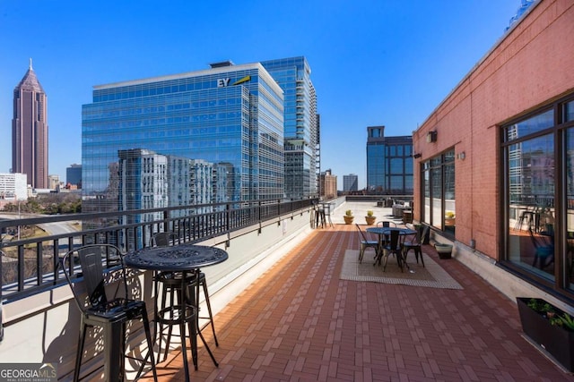 view of patio featuring a balcony, outdoor dining area, and a city view