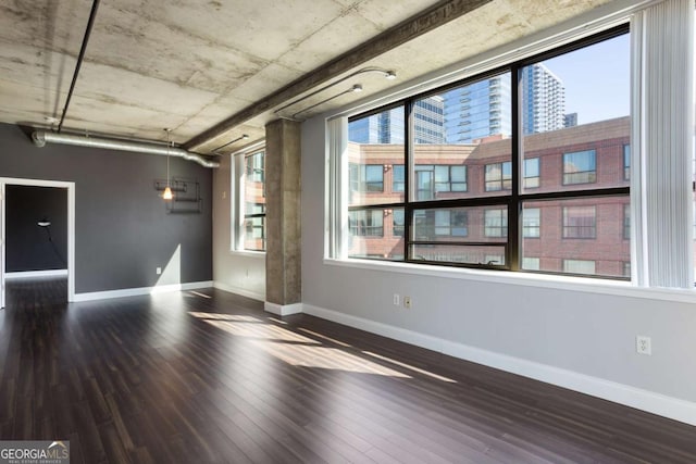 spare room with a healthy amount of sunlight, baseboards, and wood finished floors