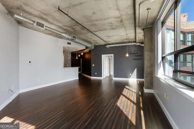 unfurnished living room featuring baseboards, visible vents, and wood finished floors