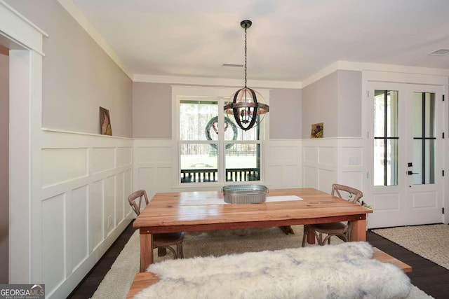 dining space with a chandelier, dark wood-style flooring, visible vents, and a decorative wall