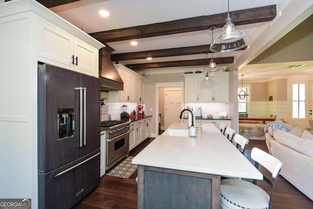 kitchen featuring premium appliances, a breakfast bar, white cabinetry, beamed ceiling, and custom range hood