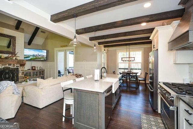 kitchen with a wainscoted wall, a sink, high quality appliances, a kitchen bar, and custom range hood